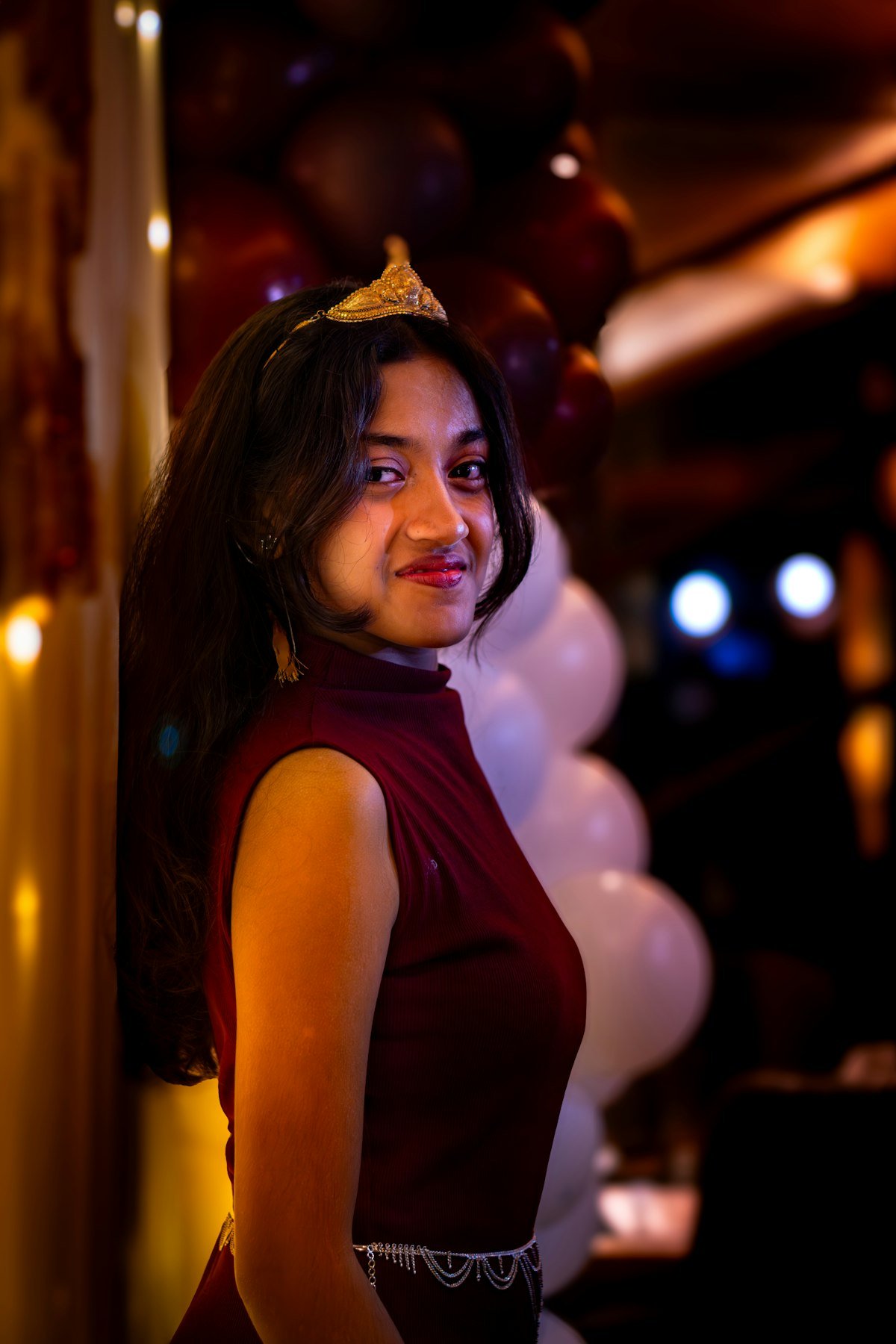 Debutante com coroa dourada celebrando a festa de 15 anos com luzes decorativas